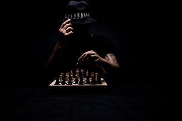 Chiaroscuro portrait of a man with a hat playing chess