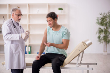 Fototapeta premium Young male patient visiting old male doctor in vaccination conce