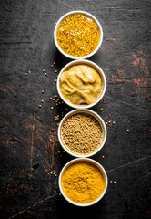 Assortment of different types of mustard in bowls.