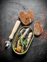 Sprats in a tin can with slices of black bread and a opener.