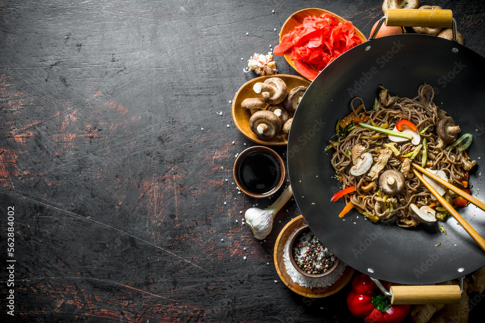 Wall mural chinese soba noodles in wok pan with ginger, spices, soy sauce, garlic and vegetables.