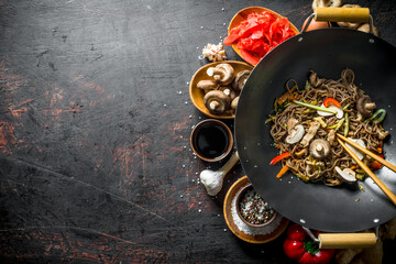 Chinese soba noodles in wok pan with ginger, spices, soy sauce, garlic and vegetables.