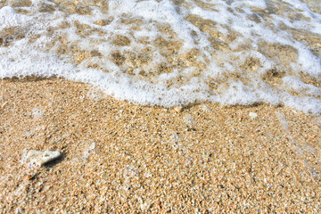 foam created by water waves and white sand on the beach	