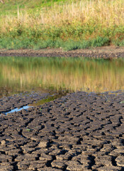 Reduction of water in the reservoir. Earth cracked because of drought. The global shortage of water on the planet. Global warming concept.