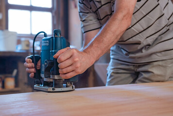 Male carpenter, working in the carpenter's workshop with power hand tools.