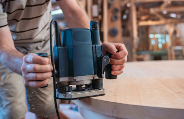 Male carpenter, working in the carpenter's workshop with power hand tools.