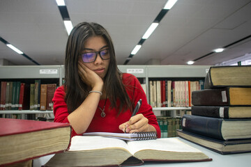 Chica universitaria con gafas estudiando en la biblioteca