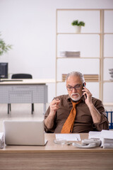 Old male employee smoking cigarette at workplace