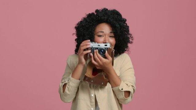 Slow Motion young African American photographer woman of color with tender face expression, taking picture of something cute and adorable moment with vintage film camera, shot on retro photo camera 4K