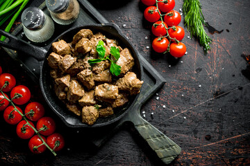 Fried liver with spices and cherry tomatoes on a cutting Board.