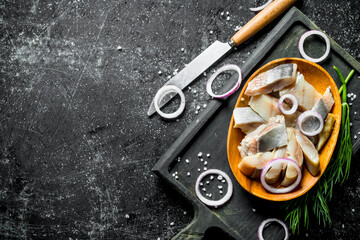 Fototapeta na wymiar Fillet of salted herring on a cutting Board with a knife, dill and onions.
