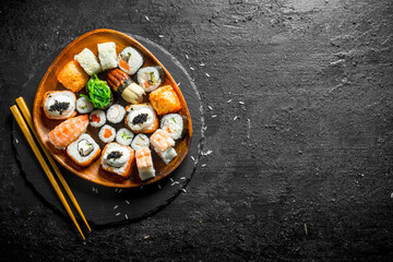 Assortment of different sushi rolls on a plate with chopsticks.