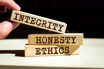 Closeup on businessman holding a wooden blocks with text 'integrity, HONESTY, ETHICS', business concept