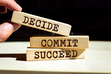 Closeup on businessman holding a wooden blocks with text 'DECIDE COMMIT SUCCEED', business concept