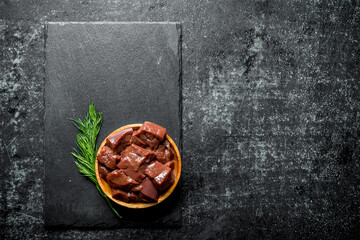 Pieces of raw liver on a plate of dill.