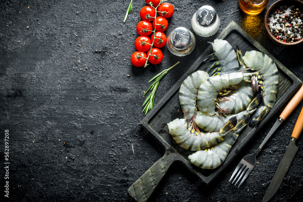 Sticker Raw shrimps on a cutting Board with cherry tomatoes and spices.