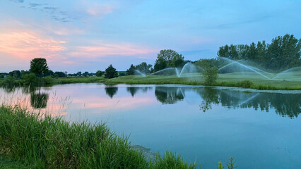 sprinklers on the golf course in the morning