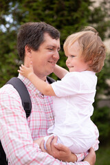 Fototapeta premium the father holds his son in his arms and hugs him. a man with a boy on the street hugging