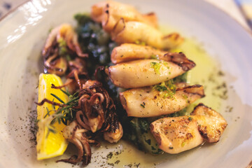 Fried grilled baby squids on a plate with garlic, lemon and mashed potato garnish served in a...