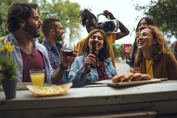 Multiethnic group of friends enjoying drinks at sunset at an outdoor bar counter