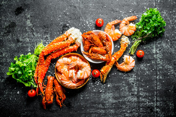 Boiled shrimp, crab and crayfish with cherry tomatoes and bunches of herbs.