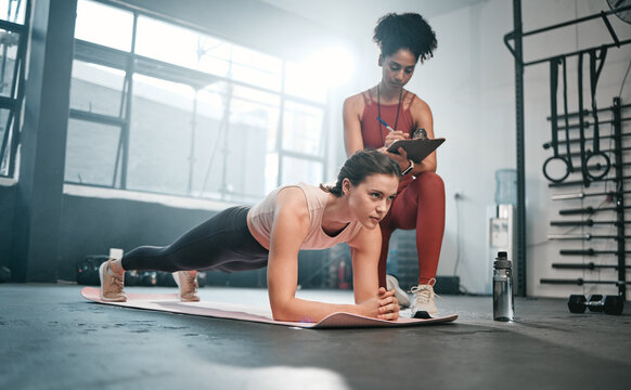 Personal trainer, fitness and clipboard with a black woman coaching a client in a gym during her workout. Health, exercise or training and a female athlete doing a plank with her coach writing notes