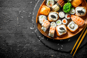 Assortment of different sushi rolls on a plate with chopsticks.