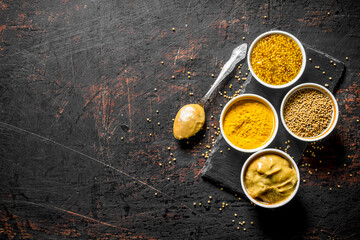 Different types of mustard on a stone Board with a spoon.