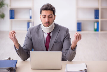 Young male employee after car accident sitting in the office