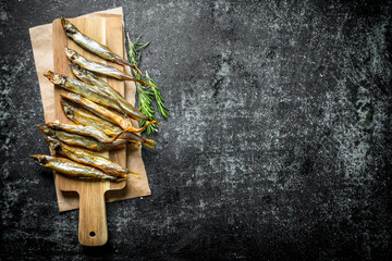 Smoked fish on a wooden cutting Board with rosemary.