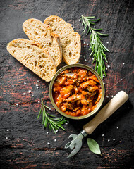 Sprat in tomato sauce in a tin can with slices of bread and rosemary.