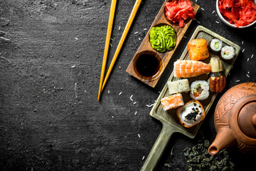 Small set of sushi rolls with green tea, ginger and soy sauce.