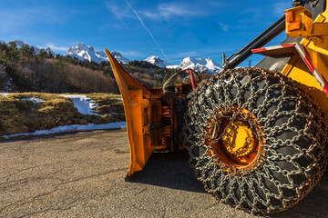 Snowplow vehicle with chains on the wheels, prepared in a snowy mountainous area.