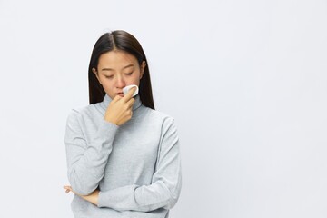 Sad Asian woman holding hand with handkerchief and coughing up flu and cold, stuffy nose viral disease asthma and allergies covid 19, white background