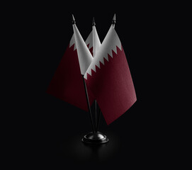 Small national flags of the Qatar on a black background