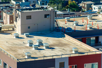 Obraz premium Rooftop under construction with cones and visible vents with roof access room and side of building shadows