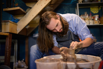 Pottery artist, Young making a piece of clay molding calmly and meticulously In order to produce...