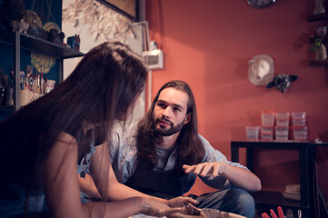 Young couples that enjoy making clay sculptures. Using pottery and assisting one another to create flower vases out of clay