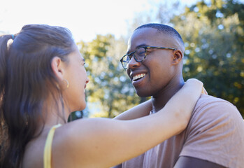 Fototapeta premium Interracial couple, smile and hug for love, care or embracing relationship together in a nature park. Happy black man hugging woman and smiling in happiness for romance, embrace or support outside