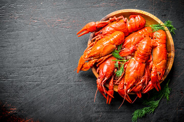 Boiled crayfish on a wooden plate with dill.