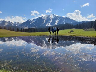 Kashmir, India - April 26 2021 : group of tourist in the valley of kashmir and reflection of mountain in pond