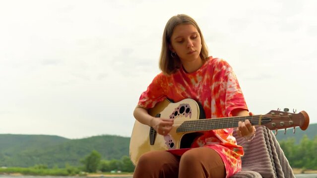 A young girl plays an acoustic guitar