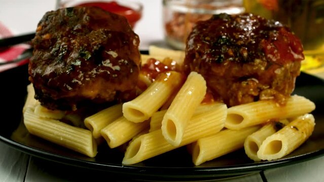 Penne pasta with meatballs pouring with tomato sau
