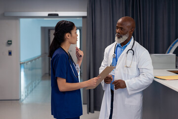 Diverse female and senior male doctor talking in hospital ward, copy space