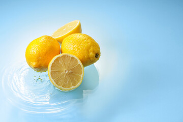 Ripe lemons on a blue background with water splashes.