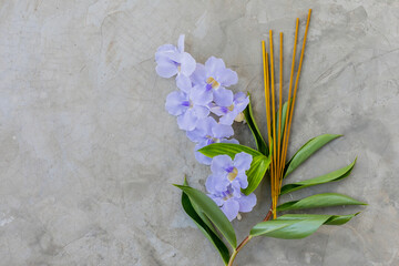 Incense sticks with violet asian flowers on concrete background with shadows top view copy space