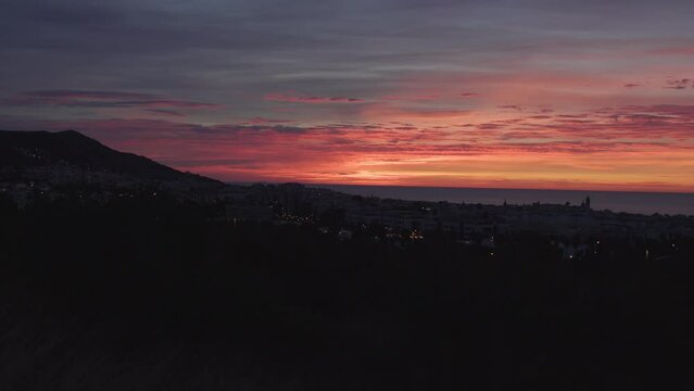 A time-lapse of a sunrise over the horizon of the sea, mountains, and city