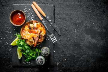 Shrimps on a stone Board with spices, tomato sauce and herbs.