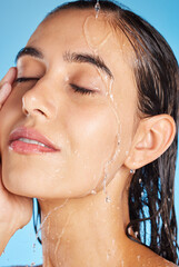 Naklejka premium Woman, shower water and face for beauty, skincare and peace with blue studio background. Calm, relax and healthy young person doing morning self face for skin glow with clean beauty treatment