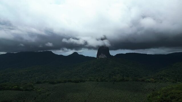 Aerial view of clouds covering the top of the Pico Cao Grande mountain, in Sao Tome - circling, drone shot